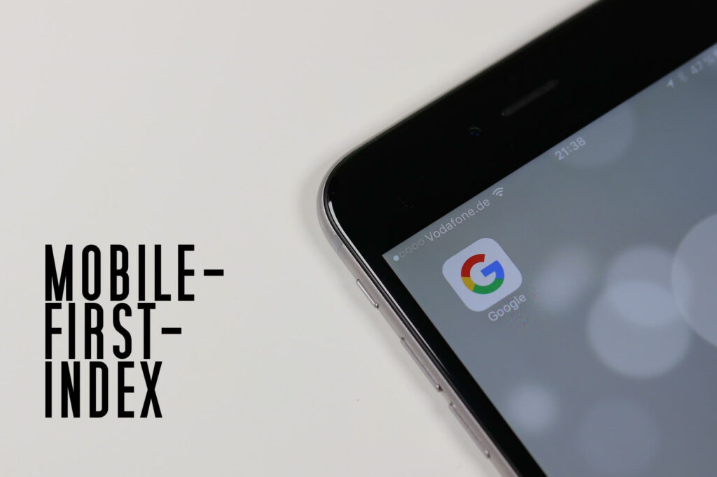 Handy auf weißer Oberfläche, daneben steht das Wort "Mobil First Index"